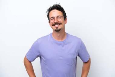 Young man with moustache isolated on white background posing with arms at hip and smiling