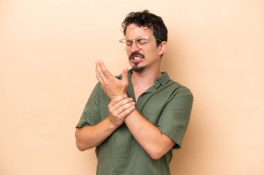 Beyazlı genç bir adam bej arka planda izole edilmiş ellerindeki acıdan muzdarip