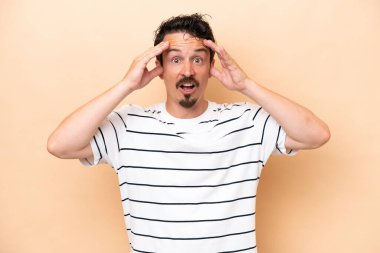 Young caucasian man isolated on beige background with surprise expression