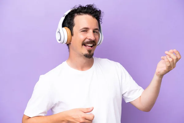 Young Caucasian Man Isolated Purple Background Listening Music Doing Guitar — Stockfoto