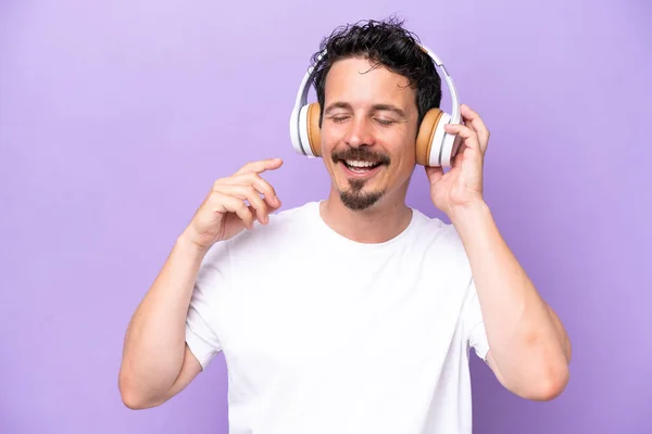 Young Caucasian Man Isolated Purple Background Listening Music Singing — Zdjęcie stockowe