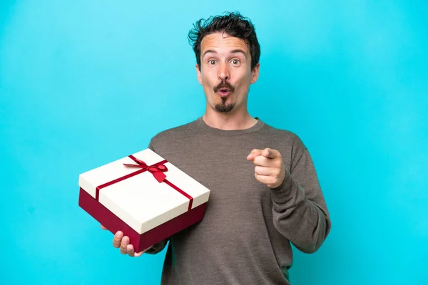 Young Man Holding Gift Surprised Pointing Front — Stock Photo, Image