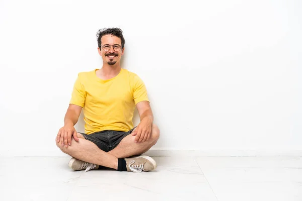 Young Caucasian Man Sitting Floor Isolated White Background Keeping Arms — Stock fotografie