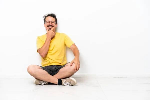 Joven Hombre Caucásico Sentado Suelo Aislado Sobre Fondo Blanco Sonriendo — Foto de Stock