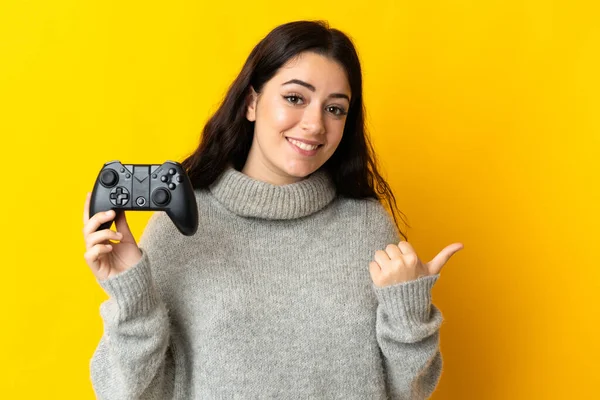 Mulher Jogando Com Controlador Videogame Isolado Fundo Amarelo Apontando Para — Fotografia de Stock