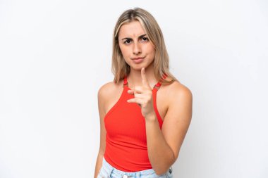 Beyaz arka planda izole edilmiş genç beyaz kadın hayal kırıklığına uğramış ve ön tarafı işaret ediyor.