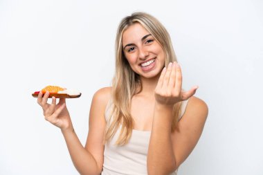 Young caucasian woman holding sashimi isolated on white background inviting to come with hand. Happy that you came