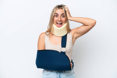 Woman with broken arm and wearing a sling isolated on white background with surprise expression
