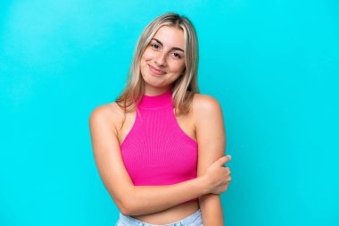 Mavi arka planda izole edilmiş genç beyaz kadın gülüyor.