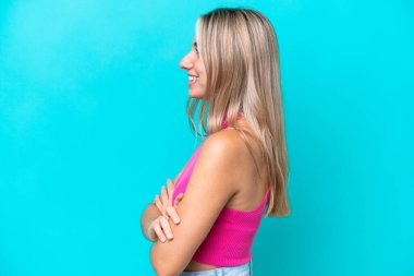 Genç beyaz kadın, mavi arka planda, yan pozisyonda izole edilmiş.