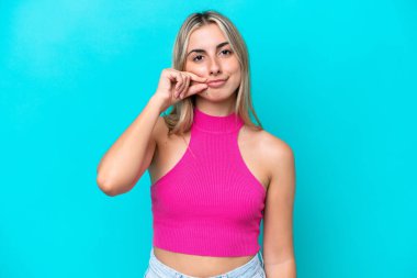 Mavi arka planda izole edilmiş beyaz bir kadın sessizlik işareti gösteriyor.