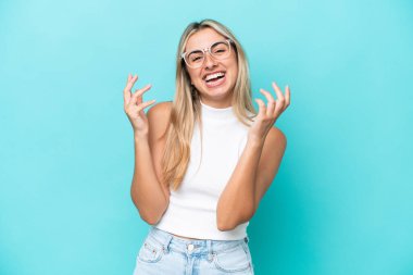 Mavi arka planda izole edilmiş genç beyaz kadın çok gülümsüyor.