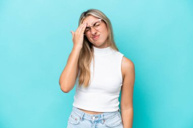 Kafkasyalı genç bir kadın mavi arka planda izole edilmiş, baş ağrısı var.