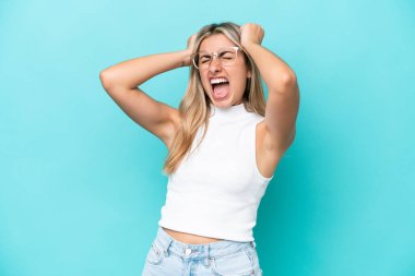 Mavi arka planda izole edilmiş genç beyaz kadın bunalımda.