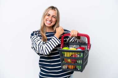 Beyaz arka planda izole edilmiş bir alışveriş sepeti taşıyan beyaz bir kadın zaferi kutluyor.