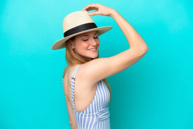 Yaz tatillerinde mayolu mavi arka planda izole edilmiş genç bir kadın.