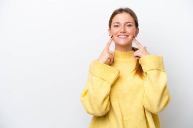 Beyaz arka planda izole edilmiş genç beyaz kadın mutlu ve hoş bir ifadeyle gülümsüyor.