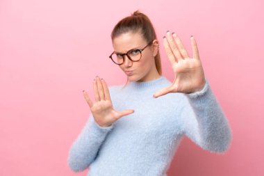 Pembe arka planda izole edilmiş genç beyaz kadın gergin ellerini öne uzatıyor.