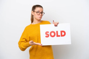 Beyaz arka planda izole edilmiş genç beyaz bir kadın. Elinde yazılı bir levha var ve onu gösteriyor.