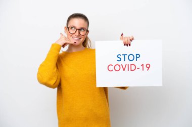 Young caucasian woman isolated on white background holding a placard with text Stop Covid 19 and doing phone gesture