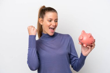 Beyaz arka planda izole edilmiş domuz kumbarası tutan beyaz bir kadın zaferi kutluyor.