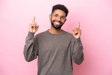 Pembe arka planda izole edilmiş genç Brezilyalı adam harika bir fikre işaret ediyor.