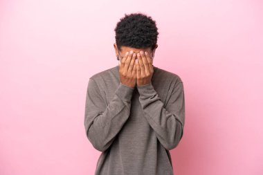 Genç Brezilyalı adam pembe arka planda izole edilmiş, yorgun ve hasta bir ifadeyle.