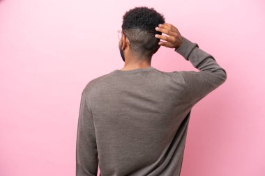 Genç Brezilyalı adam arka planda pembe arka planda izole edilmiş ve düşünüyor.