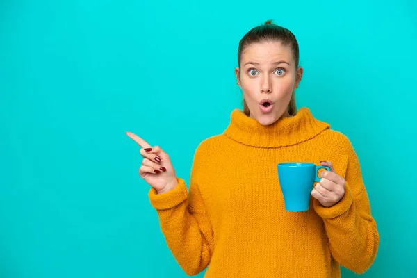 Young Caucasian Woman Holding Cup Isolated Blue Background Surprised Pointing — Foto Stock