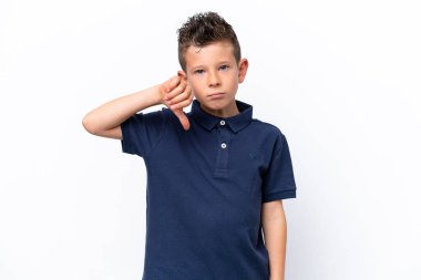 Beyaz arka planda izole edilmiş küçük beyaz çocuk olumsuz ifadeyle baş parmağını aşağı gösteriyor.