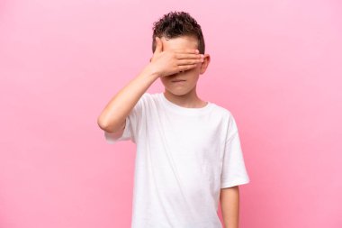 Little caucasian boy isolated on pink background covering eyes by hands. Do not want to see something
