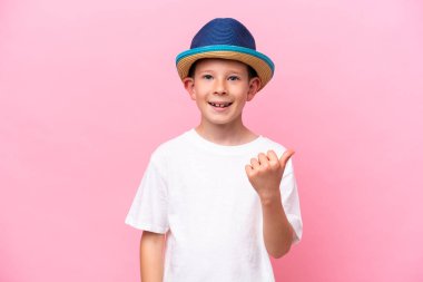 Little caucasian boy wearing a hat isolated on pink background with thumbs up because something good has happened