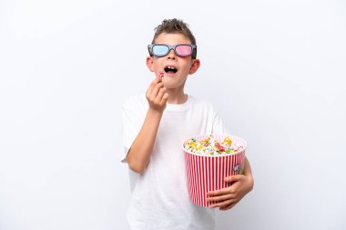 Beyaz arka planda üç boyutlu gözlüklü ve elinde koca bir kova patlamış mısır tutan beyaz tenli bir çocuk.