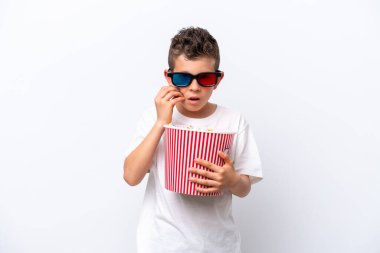 Beyaz arka planda üç boyutlu gözlüklü ve elinde koca bir kova patlamış mısır tutan beyaz tenli bir çocuk.