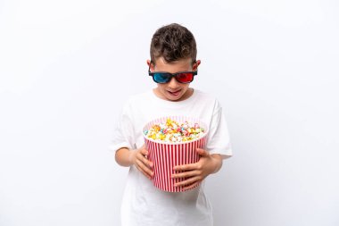 Beyaz arka planda üç boyutlu gözlüklü ve elinde koca bir kova patlamış mısır tutan beyaz tenli bir çocuk.