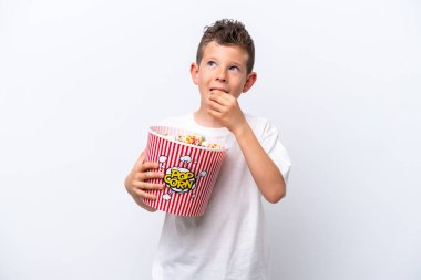 Beyaz arka planda izole edilmiş küçük beyaz çocuk elinde koca bir kova patlamış mısır tutuyor.