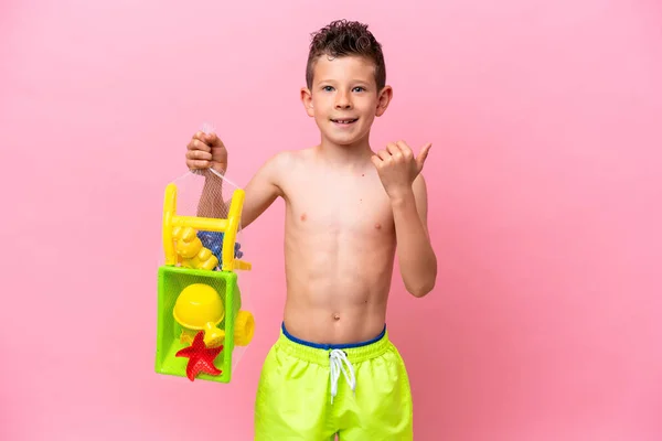 Little Caucasian Boy Holding Beach Toys Isolated Pink Background Pointing —  Fotos de Stock