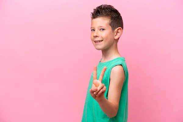 Маленький Білий Хлопчик Ізольований Рожевому Тлі Посміхається Показує Знак Перемоги — стокове фото