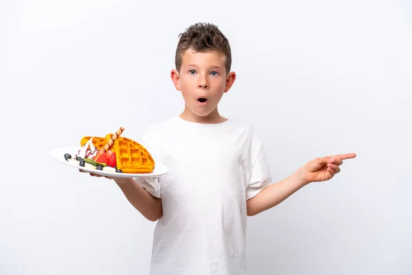 Little Caucasian Boy Holding Waffles Isolated White Background Surprised Pointing — ストック写真