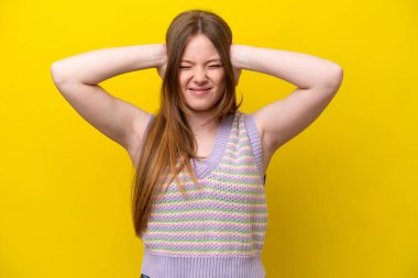 Sarı arka planda izole edilmiş genç beyaz kadın hayal kırıklığına uğramış ve kulaklarını kapatmış.