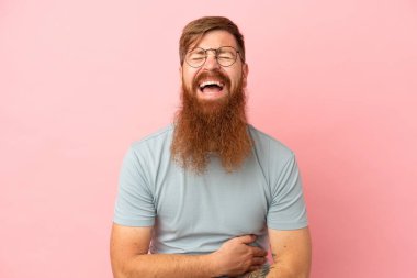 Kırmızımsı beyaz adam pembe arka planda izole edilmiş, gülümsüyor.