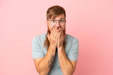 Young reddish caucasian man isolated on pink background happy and smiling covering mouth with hands