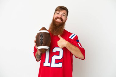 Beyaz arka planda ragbi oynayan Kafkas 'lı genç adam baş parmak hareketi yapıyor.