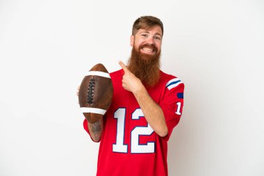 Beyaz arka planda ragbi oynayan Kafkasyalı genç adam bir ürünü sunmak için yan tarafı işaret ediyor.