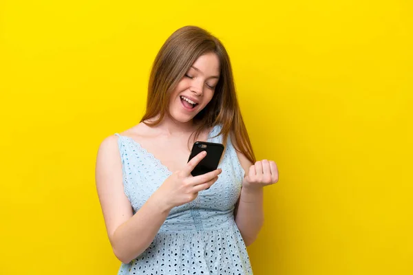 Junge Kaukasierin Isoliert Auf Gelbem Hintergrund Mit Handy Siegerposition — Stockfoto