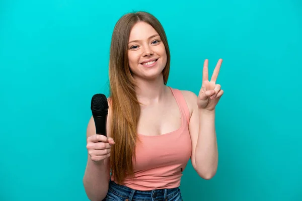 Singer Caucasian Woman Picking Microphone Isolated Blue Background Smiling Showing — Stok fotoğraf
