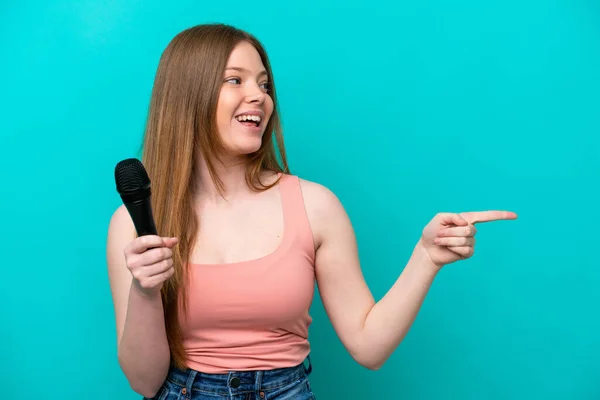 Singer Caucasian Woman Picking Microphone Isolated Blue Background Pointing Finger — Stok fotoğraf