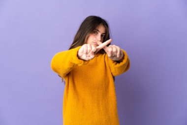 Mor arka planda izole edilmiş genç beyaz kadın bir hareketi durdurmak için eliyle jest yapıyor.