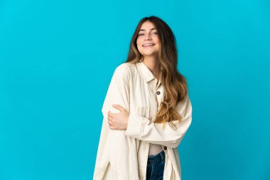 Mavi arka planda izole edilmiş genç beyaz kadın gülüyor.