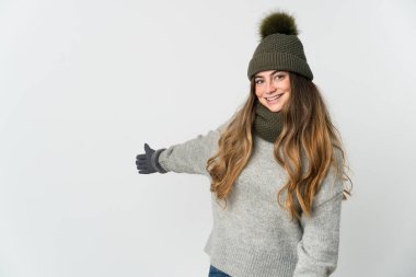 Beyaz arka planda izole edilmiş beyaz şapkalı genç beyaz kadın, davet edilmek için ellerini yana uzatıyor.